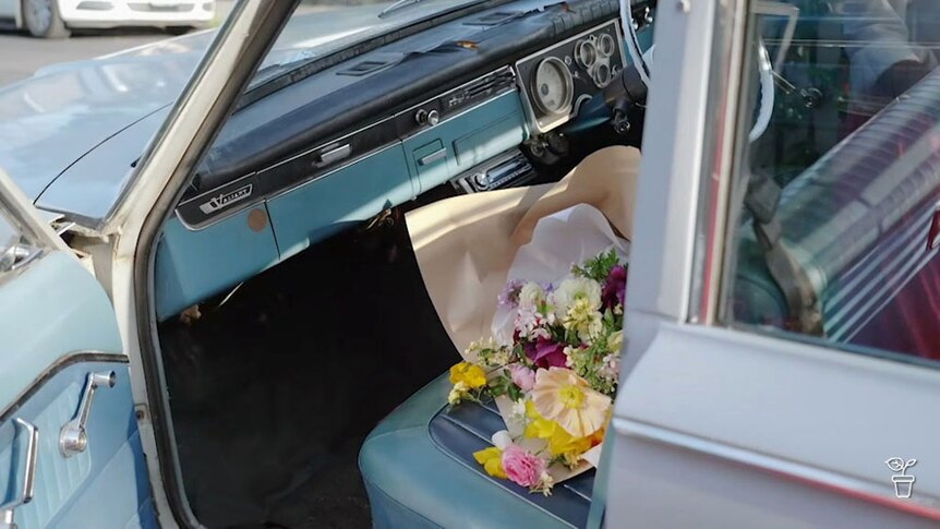 A bunch of flowers on the front seat of a vintage car.