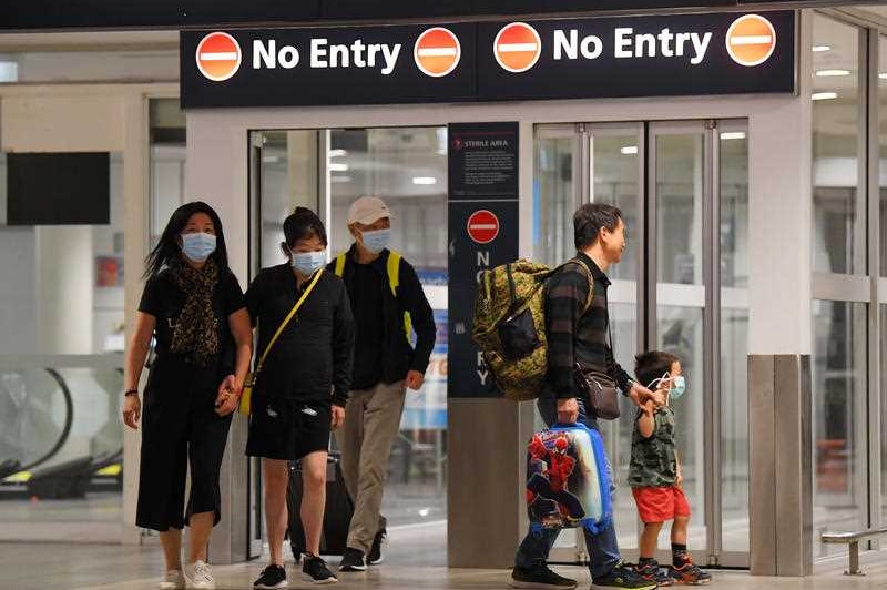 People wearing face masks walk through an airport.