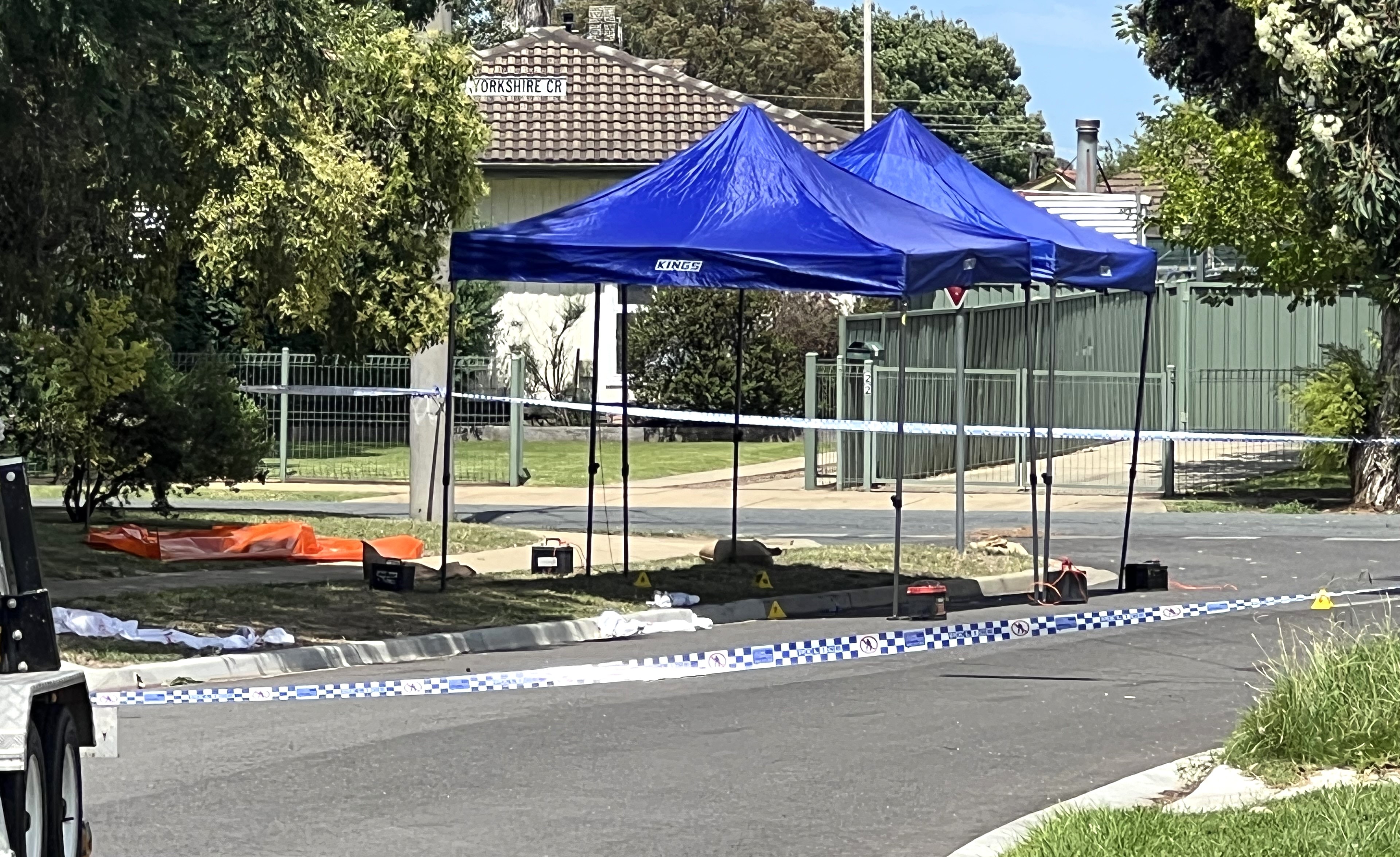 A crime scene at the front of a house cordoned off with police tape