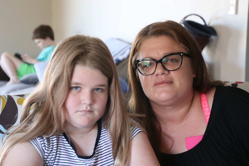 Sonya and her daughter pose for the camera with her son in the background.