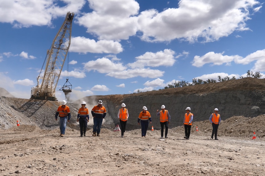 a group of eight people in high vis clothing at a mine site 