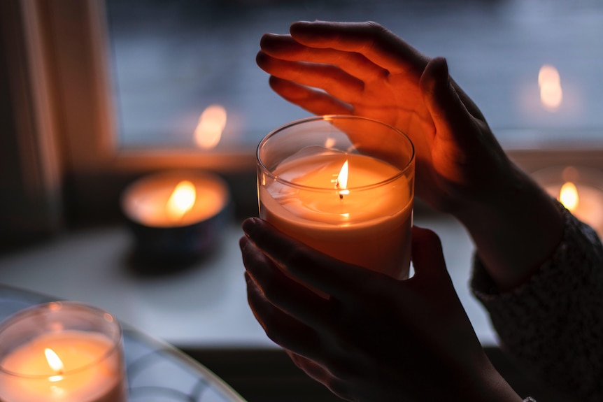 a hand waves across a lit candle