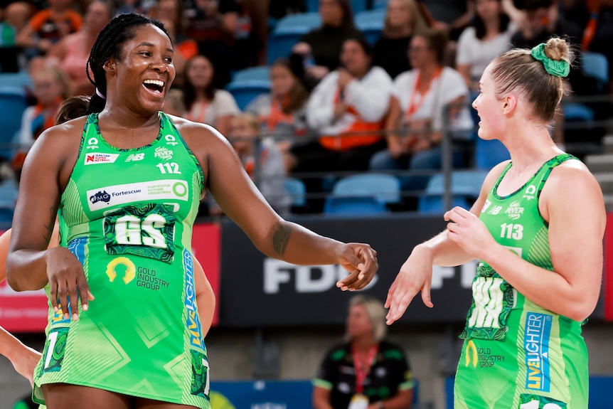 Two West Coast Fever Super Netball players celebrate the Giants' victory.