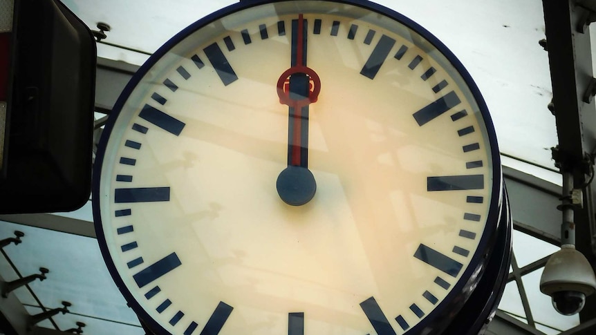 A clock strikes 12:00 at a railway station.