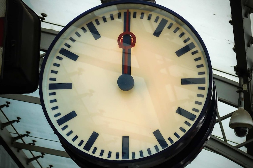A clock strikes 12:00 at a railway station.