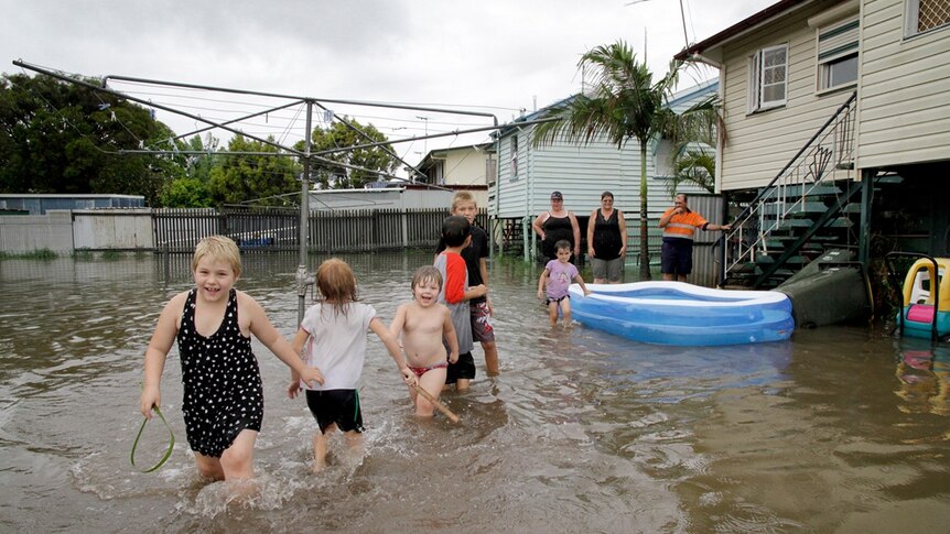 Children play in a flooded backyard in Rockhampton