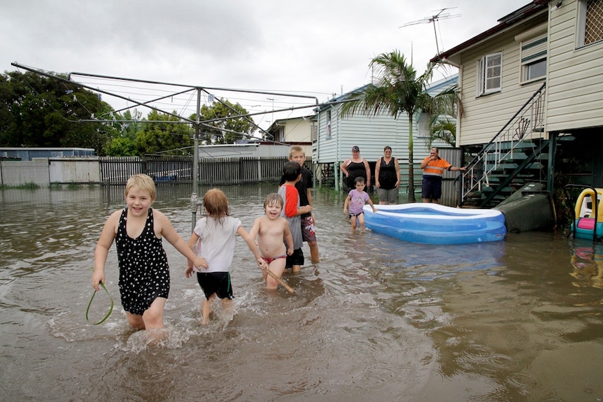 Children play in a flooded backyard in Rockhampton