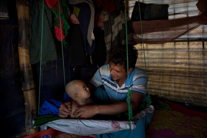 Medium shot of a man playing with a child inside a hut.