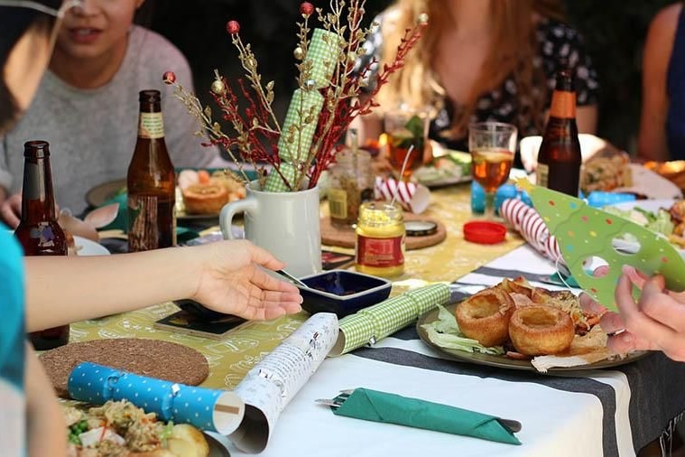 A group of unidentified people sit around a table with bonbons and drinking beers.