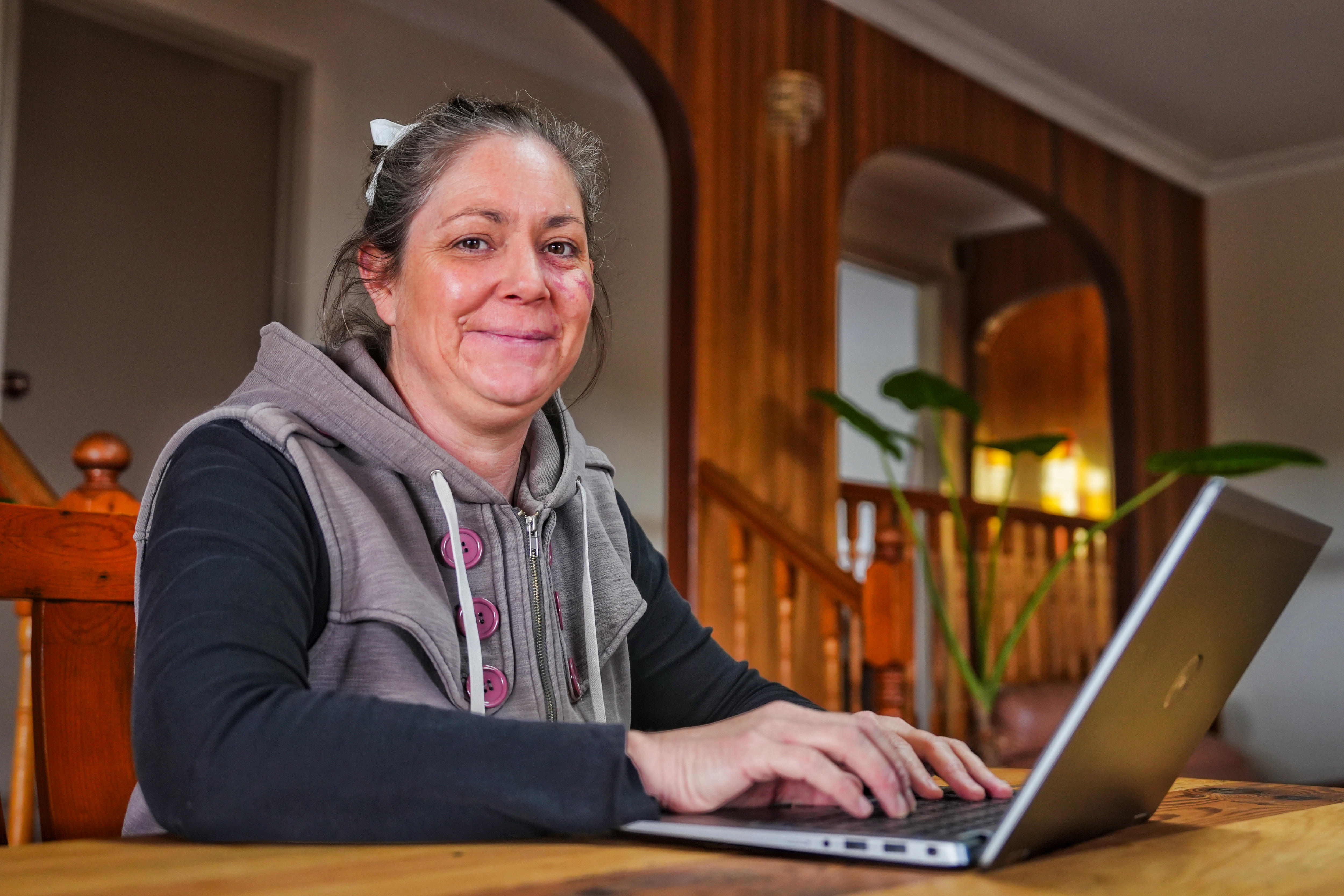 A woman sits typing at a laptop.