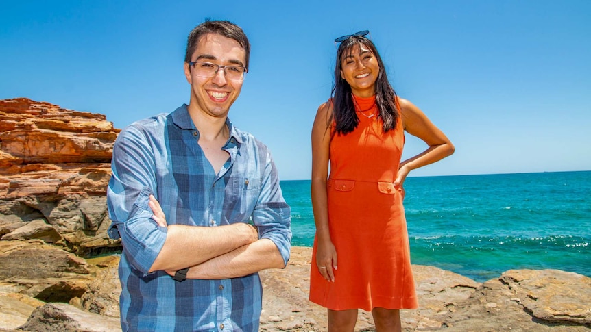 Eddie Williams and Hinako Shiraishi standing in front of the ocean on a rocky headland.