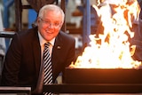 Mr Morrison looks as the camera as a flames erupt from a metal container