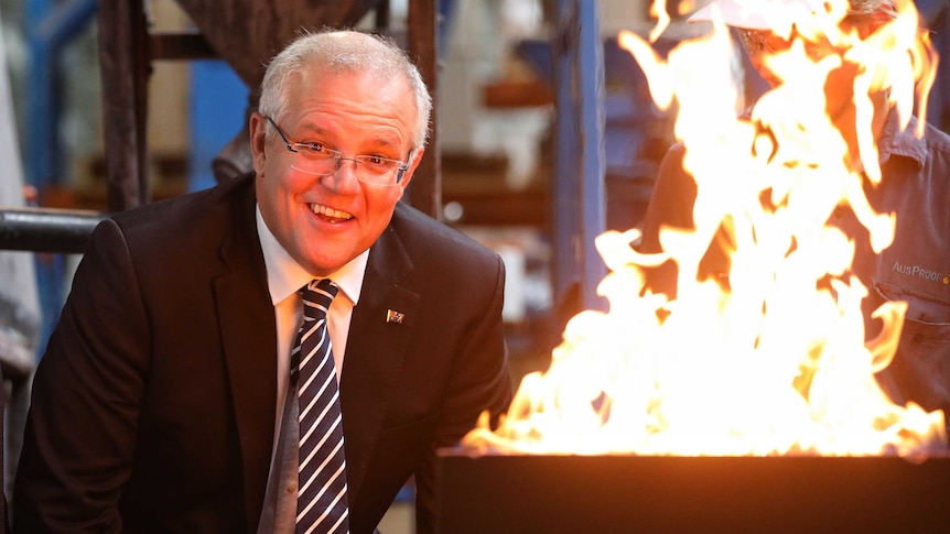 Mr Morrison looks as the camera as a flames erupt from a metal container