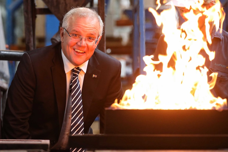 Mr Morrison looks as the camera as a flames erupt from a metal container