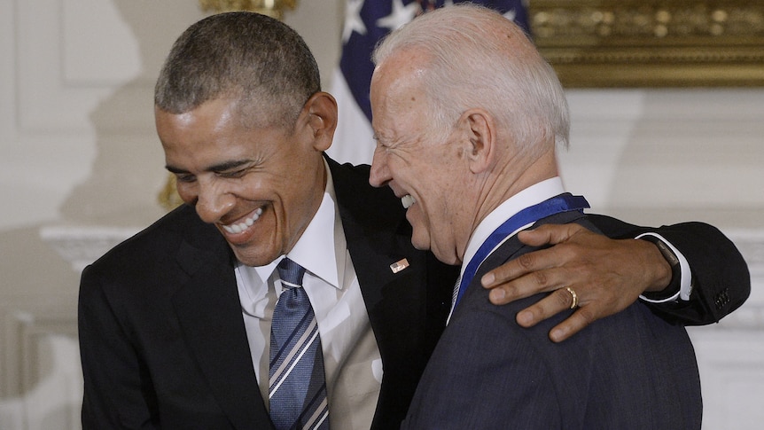 Two men close together laughing strongly and warmly, Obama's arm around Biden's shoulders
