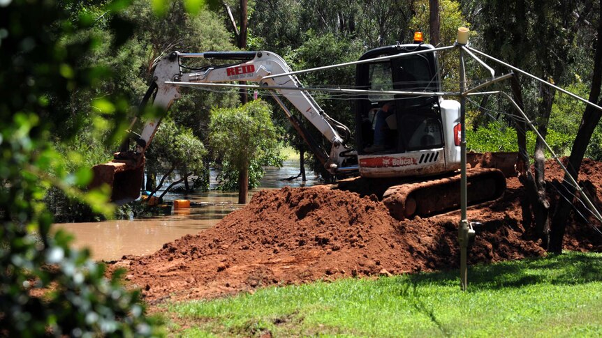 An earth mover builds a levee to protect a house in St George