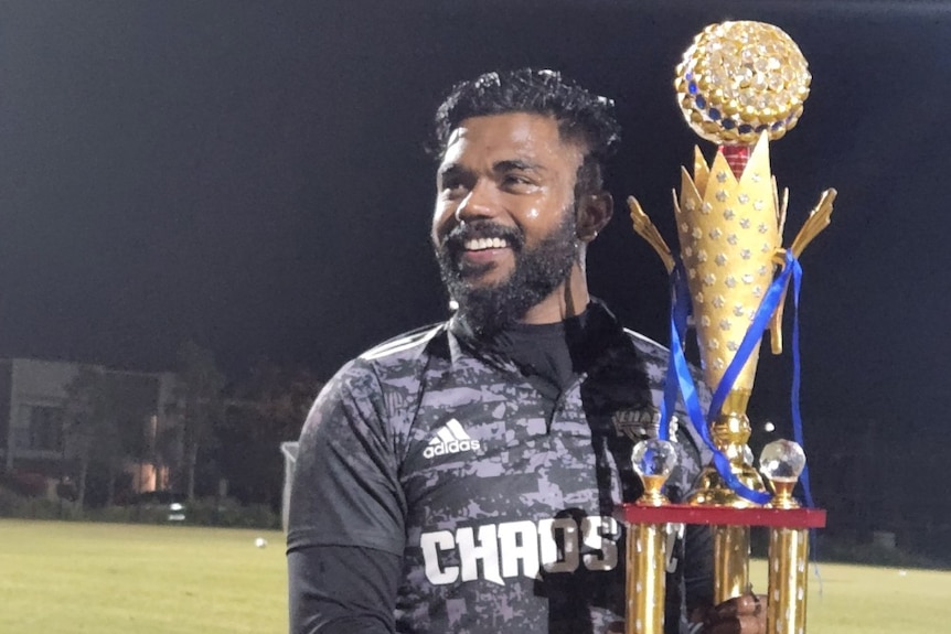 A man in black soccer gear holding a trophy