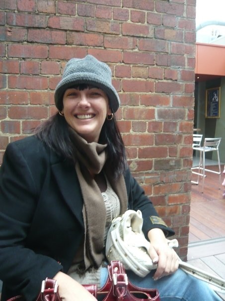 A smiling woman wears a hat and coat.