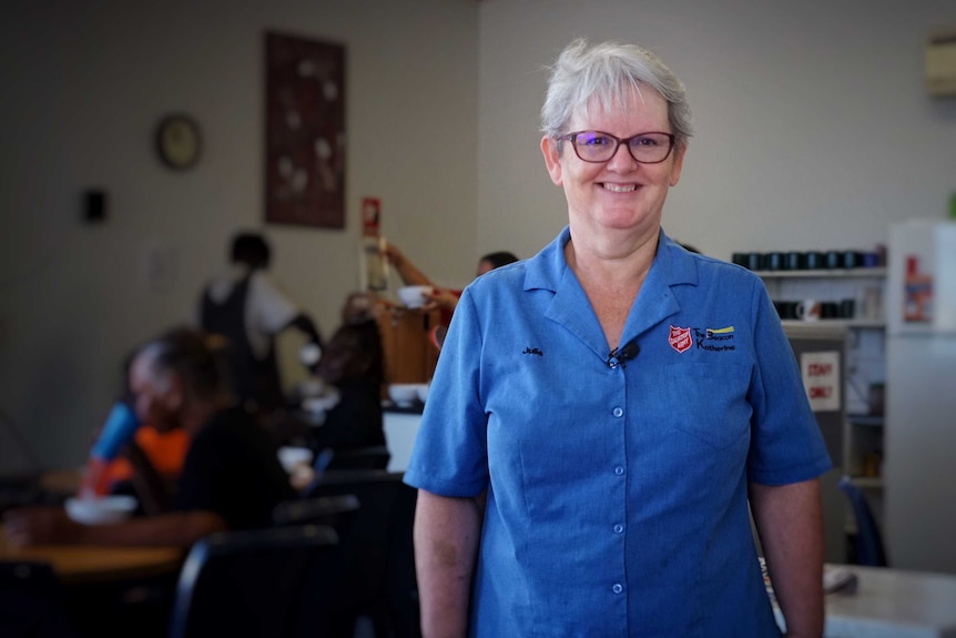 Julie Howard wears a blue Salvation Army shirt and glasses, and smiles at the camera