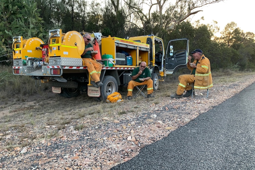 Firefighters sitting around their truck eating.