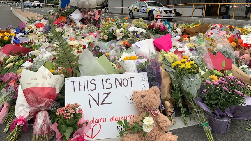 A sign reads "This is not NZ" among flowers at a growing memorial near the Al Noor mosque.