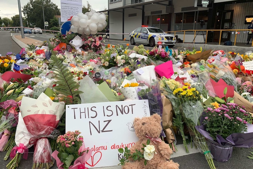 A sign reads "This is not NZ" among flowers at a growing memorial near the Al Noor mosque.