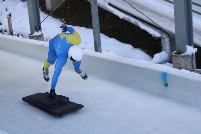 a man races down a skeleton track in the snow.