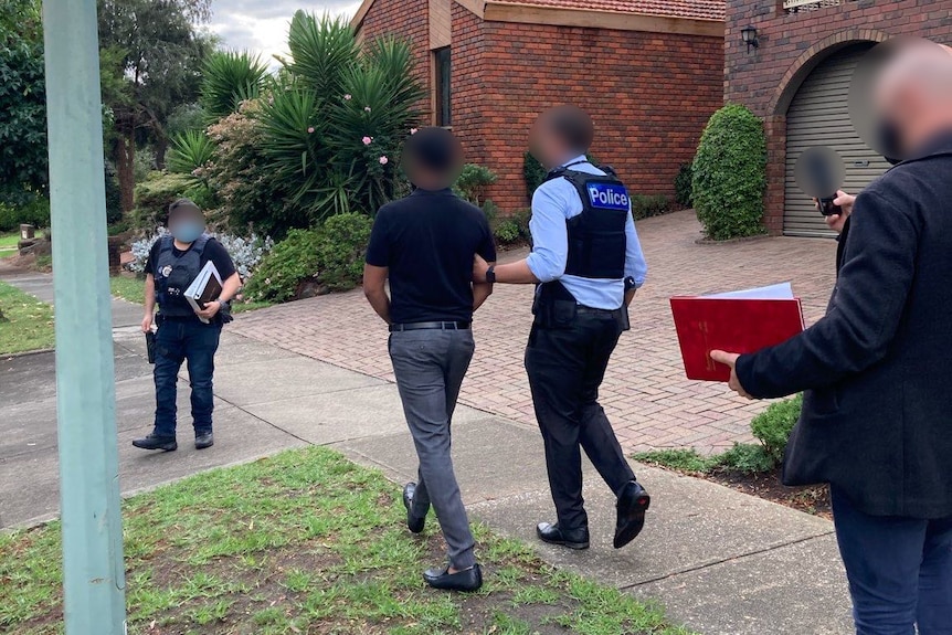 Police walk with a man in handcuffs