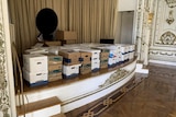 A collection of cardboard boxes sit on a stage inside a ballroom.