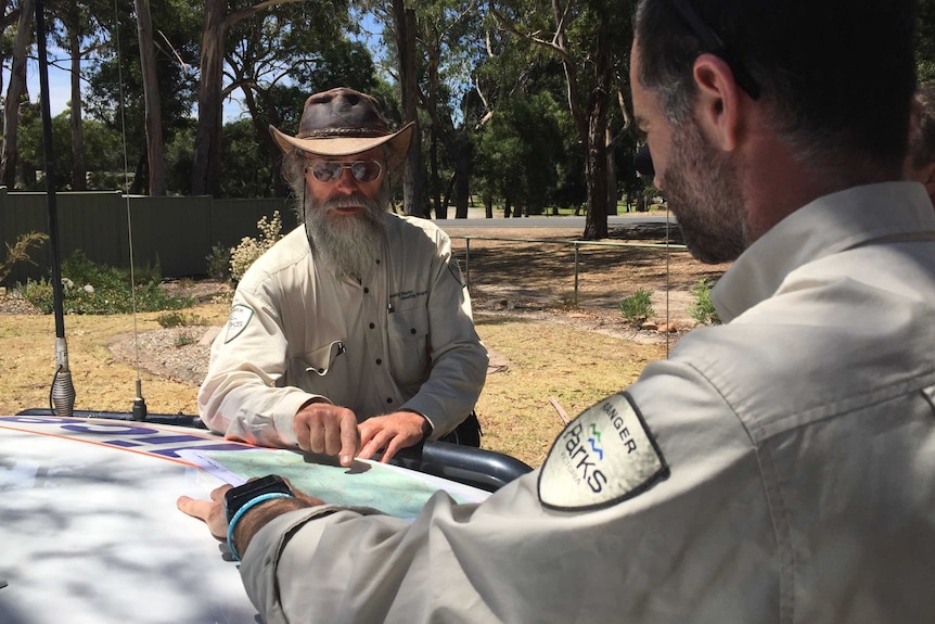 Dave Handscombe, who found missing hiker Julio Ascui, sitting at picnic table with ranger Jonno Almond.