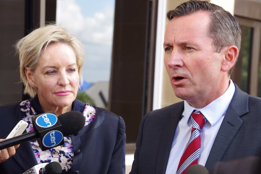 Alannah MacTiernan stands looking at Mark McGowan as he talks to reporters.