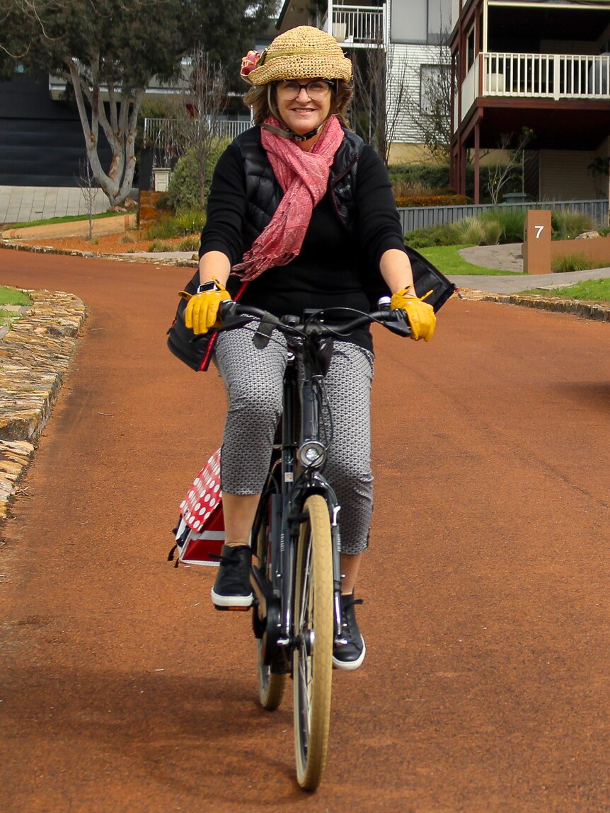 A woman rides an electric bicycle down a suburban street.