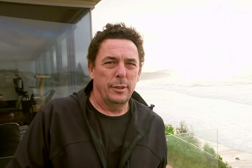 A man stands on his beachfront balcony.