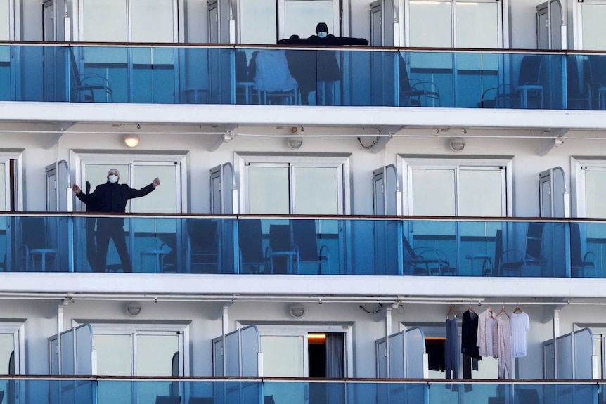 A few passengers on balconies on a cruise ship