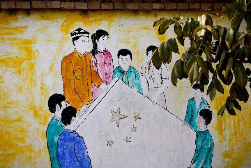 A mural showing Uighur and Han Chinese men and women holding the national flag of China.