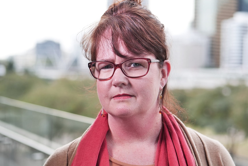 Woman with glasses looking concerned, exterior shot.