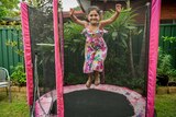 Karla De Lautour jumps on a trampoline with her arms up.