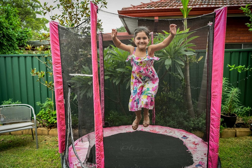 Karla De Lautour jumps on a trampoline with her arms up.