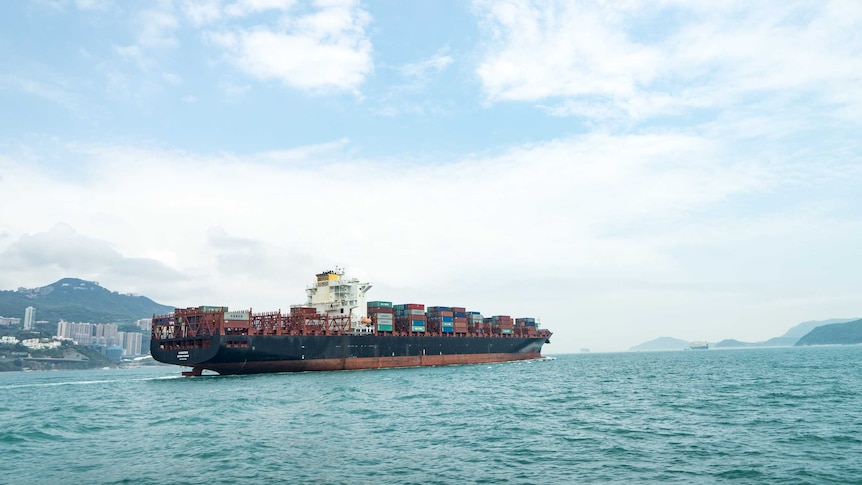 A loaded container ship travels through a harbour.