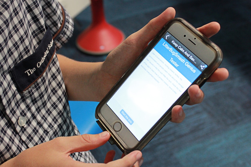 Hamish holding a phone, showing his app.