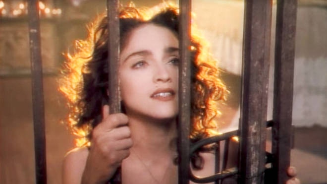 Madonna peers through an iron gate in the clip for Like A Prayer.