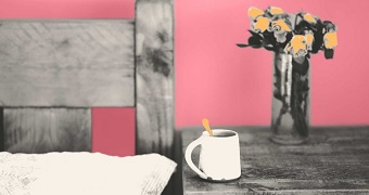 Mug sits on bedside table with vase of wilted flowers