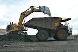 A truck is loaded with coal by a mine worker in a bob cat.