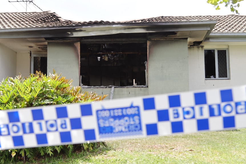 A burnt out house with police tape on the front.