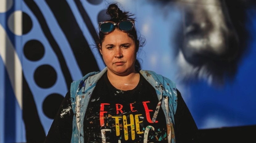 Artist Elizabeth Close stands in front of a mural.