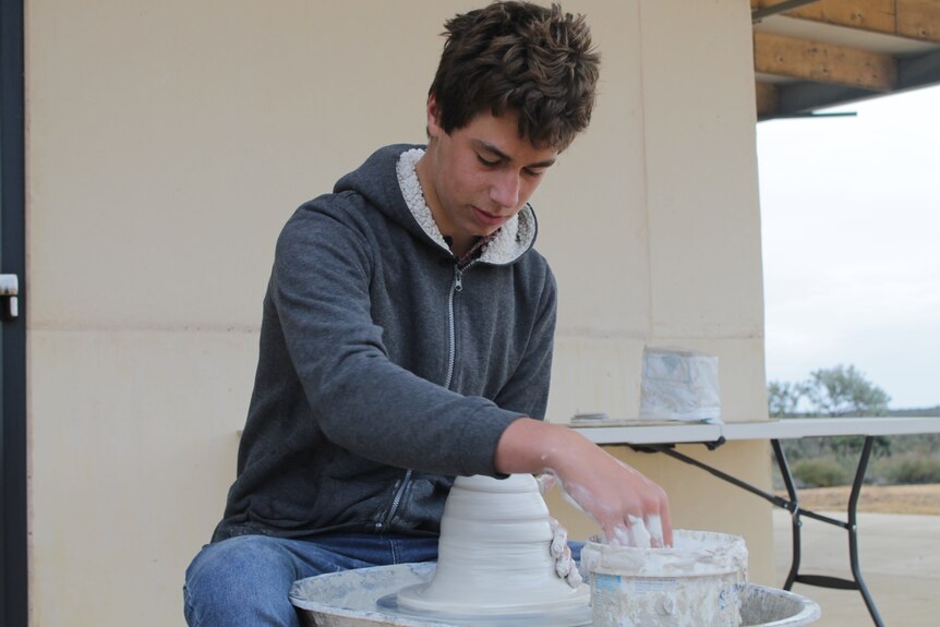 A teenage boy on a pottery wheel. 