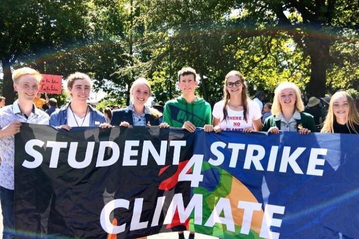 Group of school students hold a banner for the 'student strike 4 climate'.