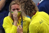 A crying Ariarne TItmus is consoled by Dean Boxall. A gold medal is around her neck