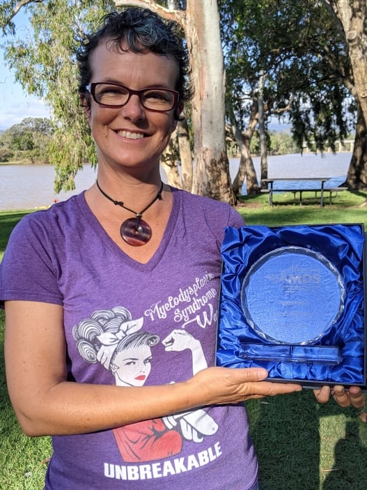 Fiona stands holding the award she received for raising awareness of a rare cancer 