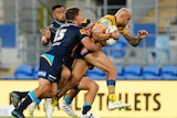 Parramatta Eels NRL player Blake Ferguson in yellow is tackled by two Gold Coast players ins dark blue.